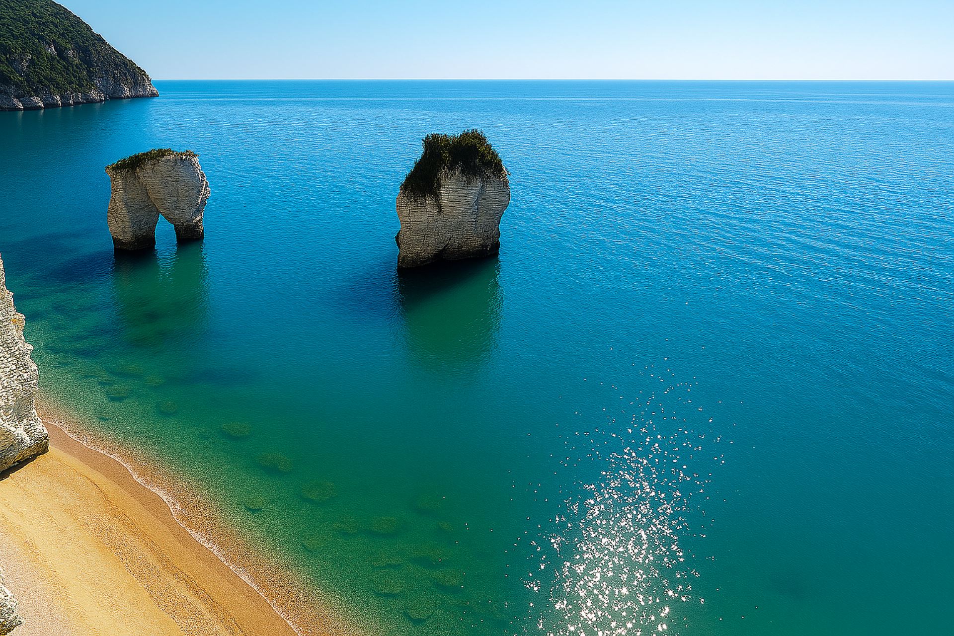 Vista panoramica della Baia delle Zagare a Vieste, con faraglioni calcarei immersi in mare turchese e spiaggia sabbiosa ai piedi delle scogliere.